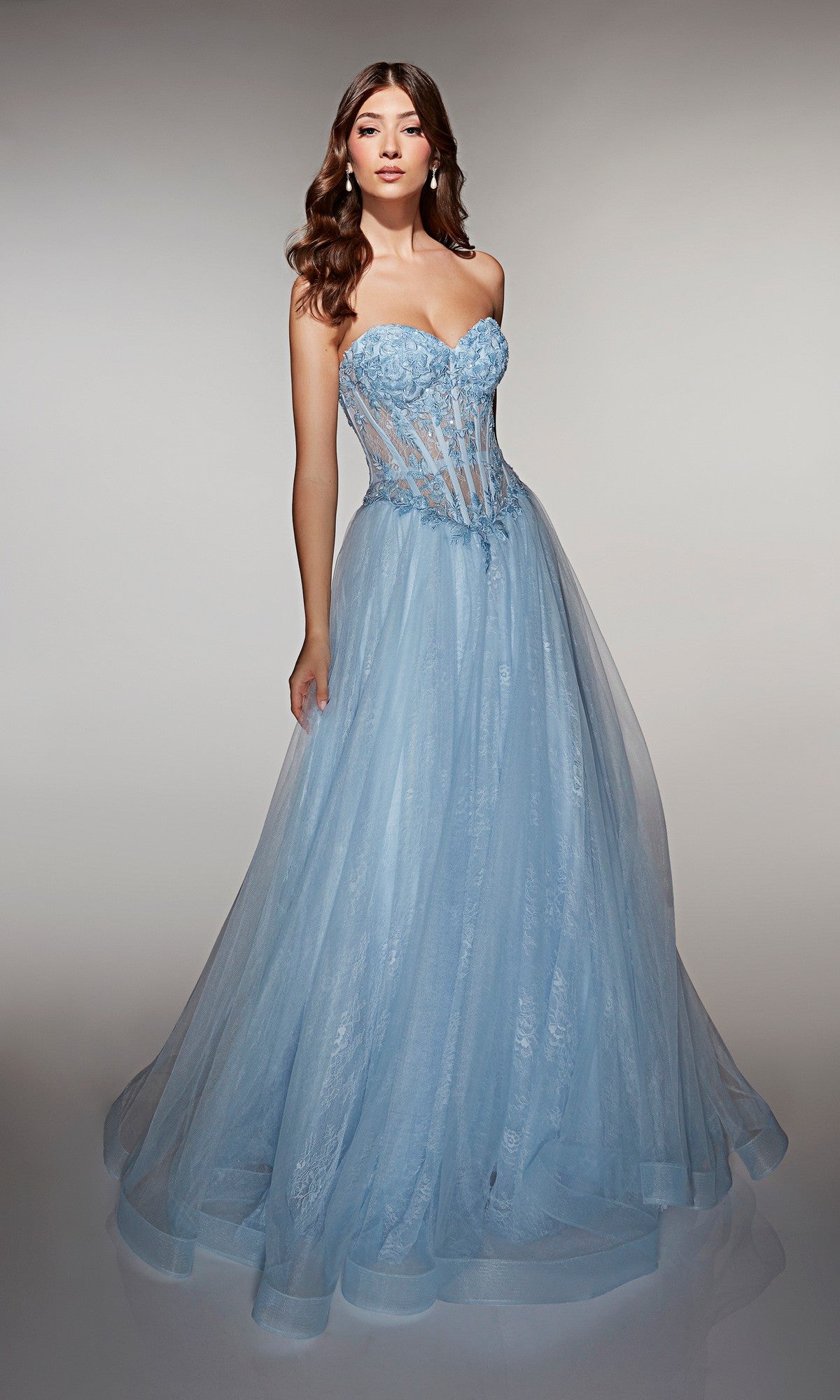 A woman models the Long Prom Dress: Alyce 61984, featuring a strapless design with a sheer corset bodice and a full tulle skirt, posed against a plain background.